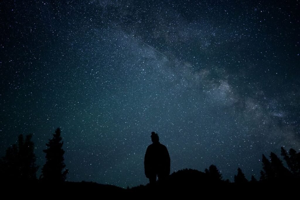 Silhouette of a person looking up at a starry night sky, reflecting on feeling stuck in life