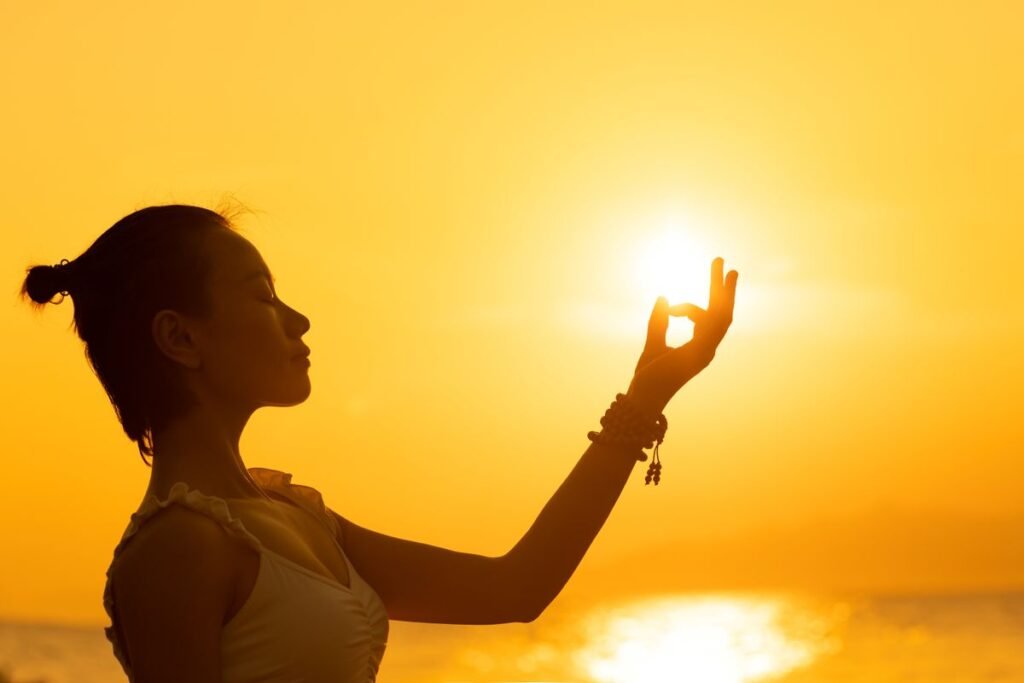 Woman meditating in front of the setting sun, representing personal growth through astrology