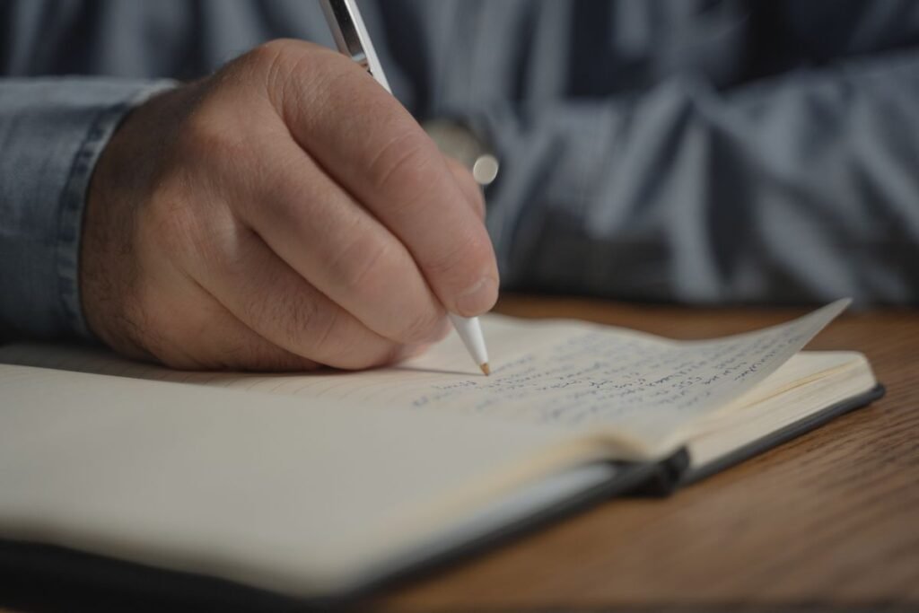 Close-up of a person writing in a notebook, journaling for self-understanding through astrology