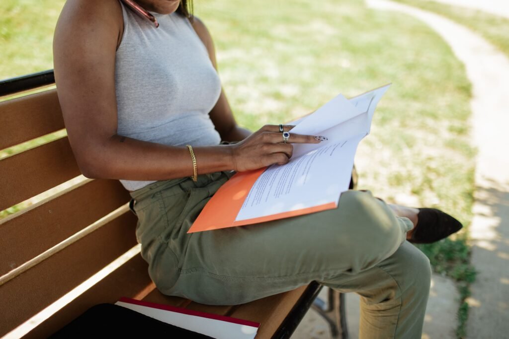 Person reading printed report pages outdoors in warm natural light, considering an astrology report purchase