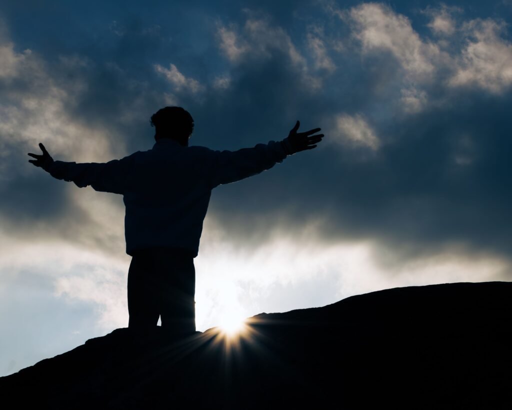 Silhouette of a person with arms raised embracing a dramatic sunrise in Tamil Nadu, representing personal growth through Vedic astrology