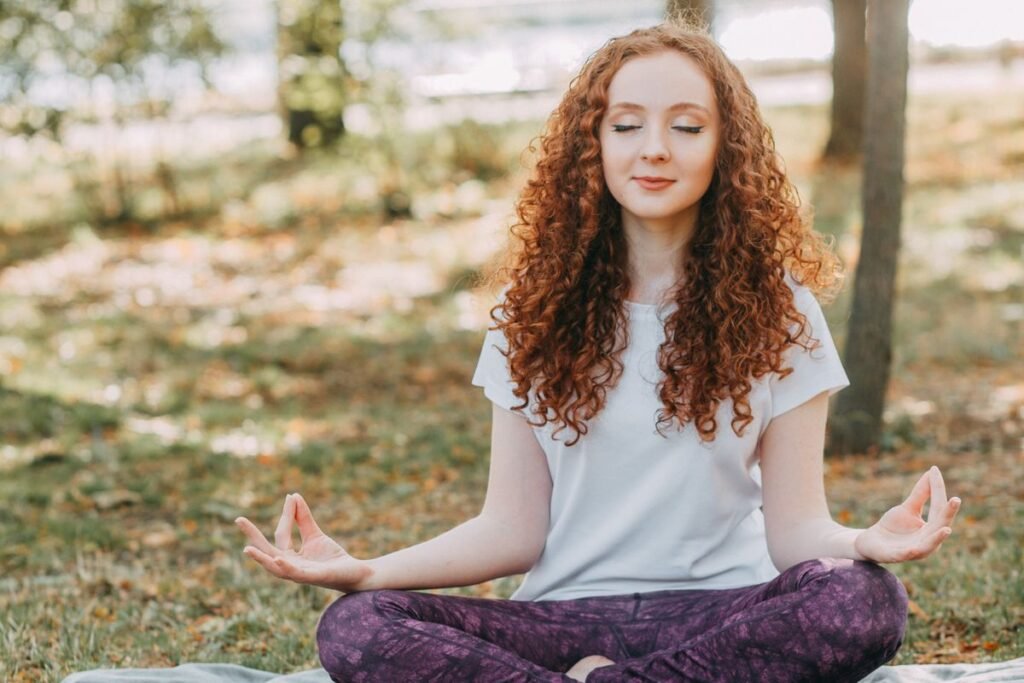 Woman meditating outdoors, representing the Vedic approach to holistic health and wellness